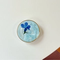 Détail d'un support de téléphone en résine bleue avec fleur séchée, perles et paillettes - Fleur de Perle à Cercle Doré / Bleu Scintillant