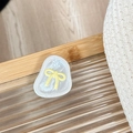 Vue détaillée du support téléphone nœud en résine sur un plateau en verre - Jaune Transparent-Nœud Papillon en Papier d'Aluminium