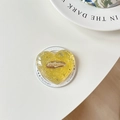 Dettaglio del supporto per telefono a cuore in resina gialla con lamina d'argento e logo - Giallo