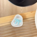 Gros plan du support de téléphone avec nœud bleu clair sur surface en verre ondulé - Bleu Transparent-Nœud Papillon en Papier d'Aluminium