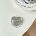 Macro shot of heart-shaped phone grip with marble texture and golden lip emblem - Gray