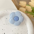 Detailed close-up of light blue flower phone grip with glossy resin finish on ceramic plate - Blue Flower