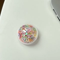 Dettaglio di paillettes iridescenti a cuore in un supporto per telefono sferico trasparente - Colorato
