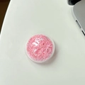 Nahaufnahme einer runden, klaren Handyhalterung mit schimmernden rosa Herz-Pailletten - Rosa