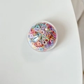 Dettaglio di un supporto circolare per cellulare con paillettes colorate su superficie bianca - Paillettes Colorate-Multicolore