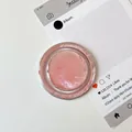 Κοντινό πλάνο κυκλικού lip balm με ροζ υφή σε διάφανη συσκευασία στο τραπέζι - Υφή Αλουμινόχαρτου Μαγνητική-Κόκκινο