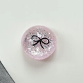 Dettaglio del supporto per telefono rosa glitterato con un motivo a fiocco nero - Supporto Sfera di Cristallo-Pois Glitter Fiocco Nero / Rosa