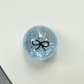 Macro detail of a light blue glitter ball phone stand with a black bow pattern - Crystal Ball Stand-Dots Glitter Black Bowtie / Blue