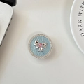 Close-up of sparkling rhinestone bow phone grip with pink heart gem on blue base - Blue