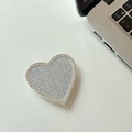 Dettaglio del supporto per telefono a cuore con strass scintillanti su tavolo bianco - Argento