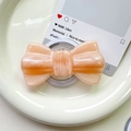 Macro view of pearlescent orange-pink glitter bow magnetic phone grip on ceramic plate - Pearlized Large Bowknot-Orange