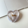 Detail view of heart-shaped MagSafe grip with silver pearlescent finish and Smile text - Magnetic Large Crooked Heart Glitter Gold Smile / Brown