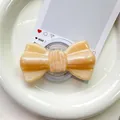 Macro detail of magnetic peach glitter bow phone socket with transparent round base - Pearlized Large Bowknot-Yellow