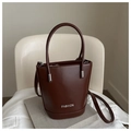 Detailed macro view of the silver FASHION lettering on a brown leather bucket bag - Dark Brown