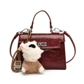 Deep red patent leather Kelly handbag with a cute plush bear charm on white background - Red with Pendant