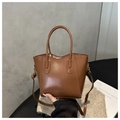 Détail d'un sac seau en cuir marron avec lettrage FASHION et garnitures dorées - Beige