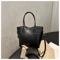 Detalle del bolso tote minimalista de cuero negro con hebilla dorada y letras de logo - Negro