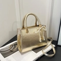 Chic gold metallic crossbody bag with pearl bow charm on a minimalist art book - With Pendant / Gold