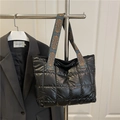 Black quilted puffer tote bag with blue patterned handles on a display rack - Black