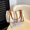 Borsa tote in tela a righe con manici in finta pelle marrone su una sedia beige - Bianco Sporco