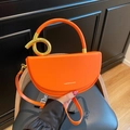 Chic orange saddle bag with golden circular metal handle and adjustable long strap - Orange