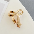 Makrodetail eines galvanisierten goldenen Schleifen-Handyhalters mit edler Metallstruktur - Transparenter Epoxid-Ständer - Glänzende Dear Schleife - Gold