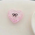 Dettaglio supporto telefono a cuore rosa glitterato con fiocco nero su fondo beige - Cuore 3D Pois Glitter Fiocco Nero / Rosa