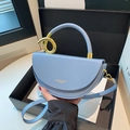 Hellblaue Satteltasche in Halbmondform mit goldenem Ringgriff und schmalem Schultergurt - Blau