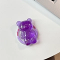 Detail of purple bear phone grip with gold flakes and Good Luck text on white desk - Dark Purple