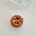 Detail of a brown resin button phone socket with a suede bow on a clean white surface - Brown Bow Button