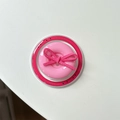 Macro view of pink button phone grip with suede bow detail on a transparent base - Magnetic Bow Button / Rose Red
