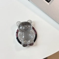Detail of bear phone socket with gold foil and Good Luck text on white desk - Black