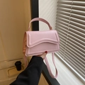 Close-up of light pink crossbody bag with wavy stitching and gold hardware detail - Pink