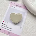 Gros plan du support de téléphone beige en forme de cœur avec finition en résine brillante - Gris Laiteux