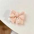 Close-up of a pink bow-shaped expandable phone grip with a glossy resin finish on white surface - Pink