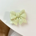 Detail of light green bow phone grip with glossy finish and retractable design - Green