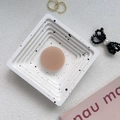 Detail view of a matte nude round phone grip stand placed on a modern white spotted tray - Milk Tea
