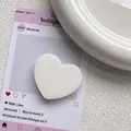 Close-up of a white heart-shaped expandable phone socket with a smooth glossy finish - White