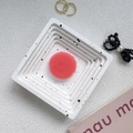 Detailed top view of a translucent pink round phone grip on a white speckled ceramic tray - Coral