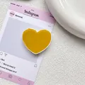 Détail d'un accessoire de support de téléphone en résine jaune brillant en forme de cœur - Curcuma