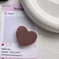 Gros plan d'un support de téléphone en forme de cœur marron avec une finition lisse - Café