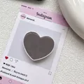 Gros plan d'un support de téléphone en forme de cœur gris foncé sur une carte esthétique - Gris Café