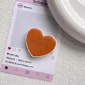 Détail du support de téléphone en forme de cœur orange vif avec finition en résine brillante - Orange Morandi