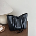 Minimalistische schwarze PU-Leder Tote Bag mit Goldlogo auf Holztisch, große Kapazität - Schwarz