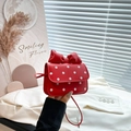Red crossbody bag with white polka dots and a large bow shown in a lifestyle hand-held view - Red