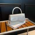 Bolso de mano plateado con brillo y solapa ondulada en banco de madera oscura - Plateado