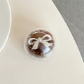 Close-up of a round mink fur phone grip with a white bow on a minimalist desk - Brown