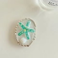 Macro view of ocean style starfish phone grip with silver wavy border and pearl detail - Green