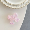 Macro view of a pink iridescent bow phone grip with heart detail on a white surface - Iridescent Pink