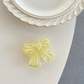 Detail of iridescent green bow-shaped expanding phone grip on white table - Iridescent Yellow
